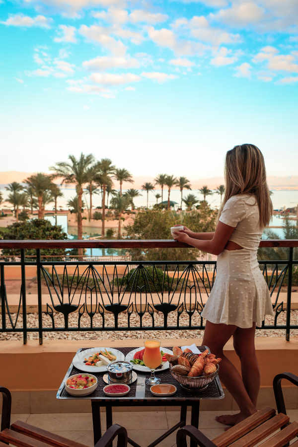 a girl stands in the balcony of mosaique's room and a breakfast with a view to Red Sea